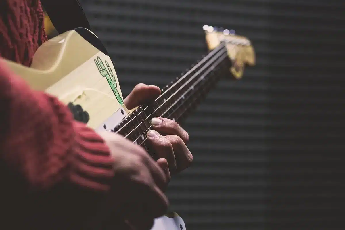 Musician wearing headphones studying a bass line on a laptop