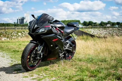 Silhouette of a fully-faired supersport bike parked by a curving coastal road at golden hour