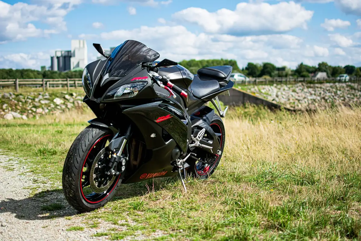 Silhouette of a fully-faired supersport bike parked by a curving coastal road at golden hour