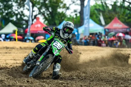 Two anonymous racing motorcycles neck-and-neck on a dirt oval with blurred grandstand