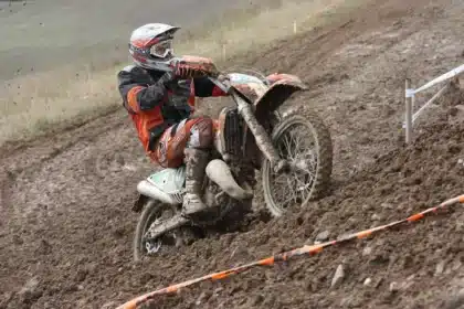 Silhouette of an off-road motorcycle and rider crossing a dusty backcountry track