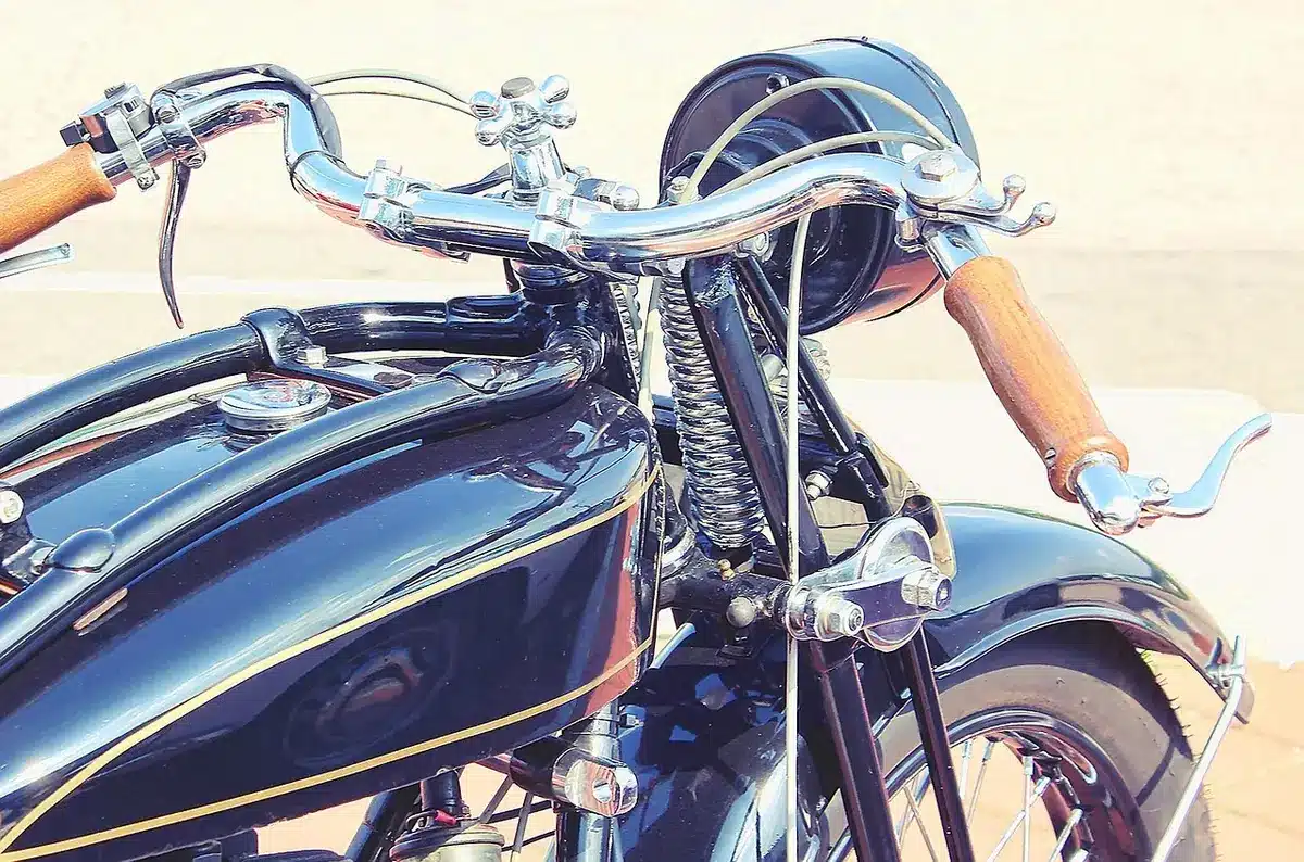 Close-up of a broad fuel tank and period-style handlebars on a retro motorcycle