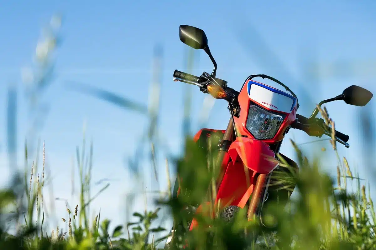 Silhouette of an unbranded dual-sport motorcycle parked by a country lane with a gloved hand on the throttle