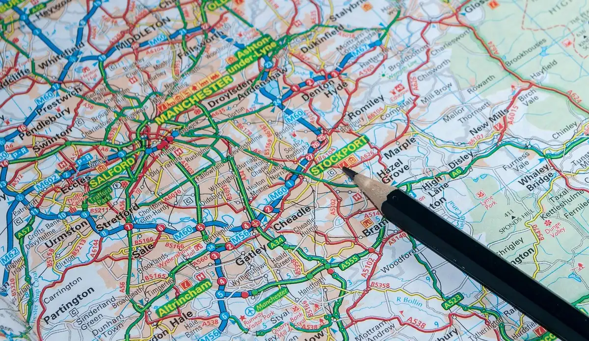 Hands holding a paper route map next to a coffee cup in a café