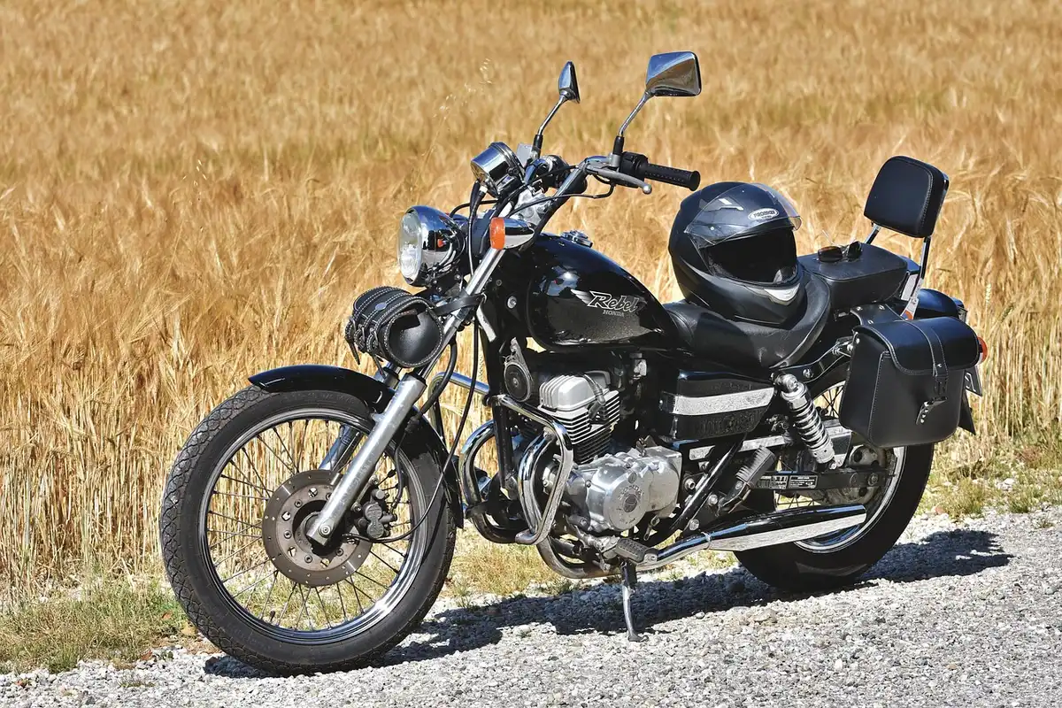 Row of parked mid-size motorcycles by a cafe, anonymous riders in background