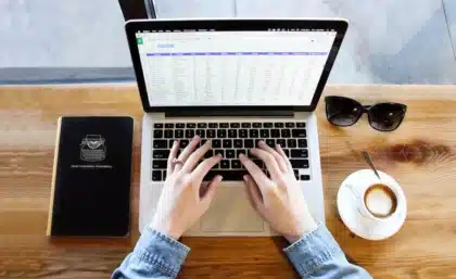 Hands adjusting an EEG headset beside a laptop displaying abstract brainwave signals