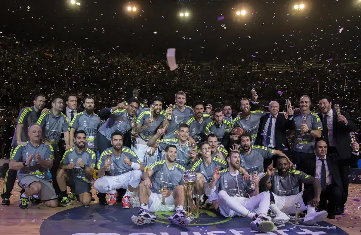 Champion on podium holding trophy with team celebrating