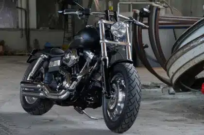 Two motorcycles strapped on a trailer beside a parked car on the roadside