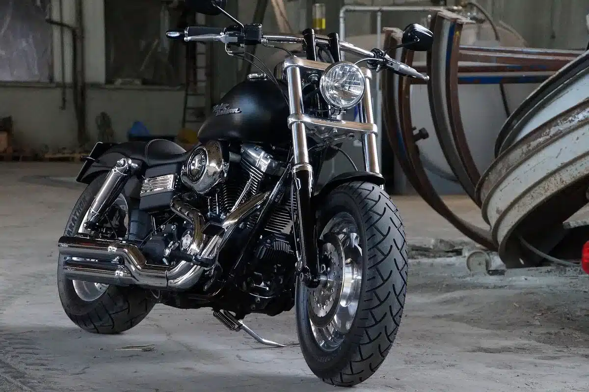 Two motorcycles strapped on a trailer beside a parked car on the roadside